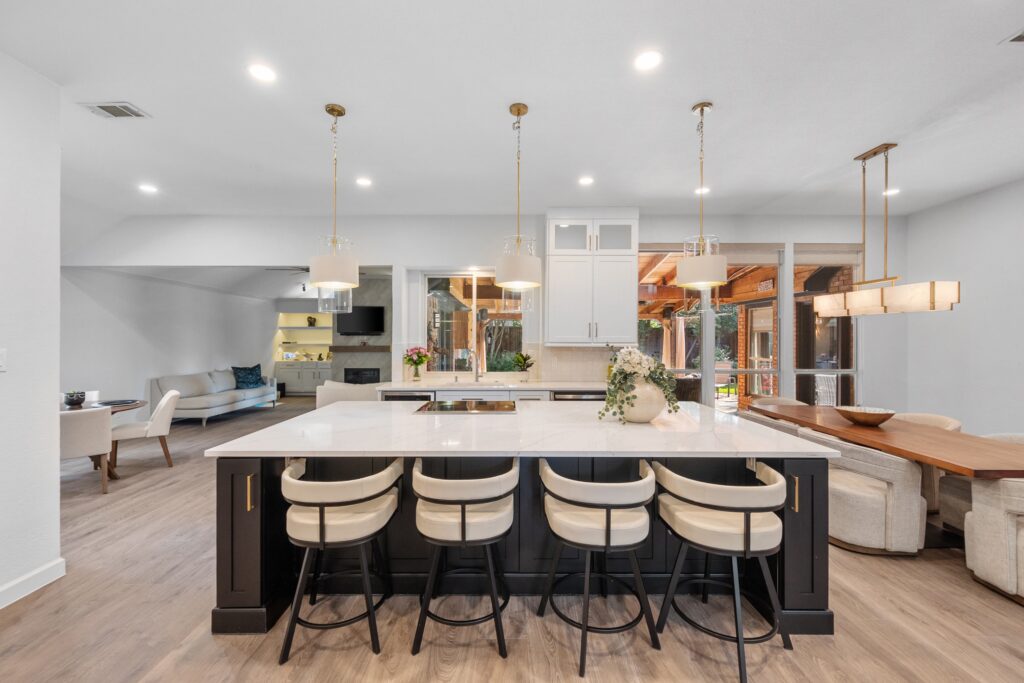 Open-concept kitchen with a black island and four cream stools