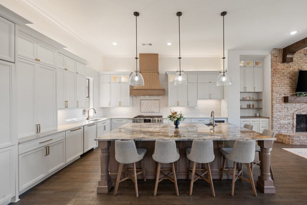 Kitchen with a marble island, wood hood, and brick fireplace