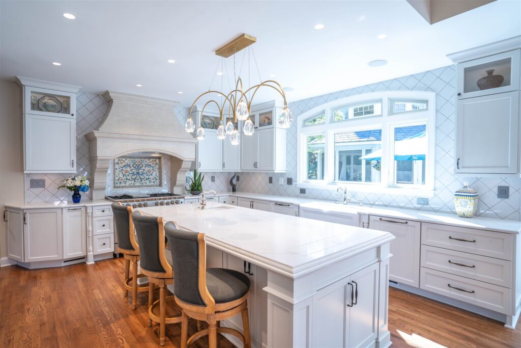 White kitchen with a stone range hood and arched chandelier